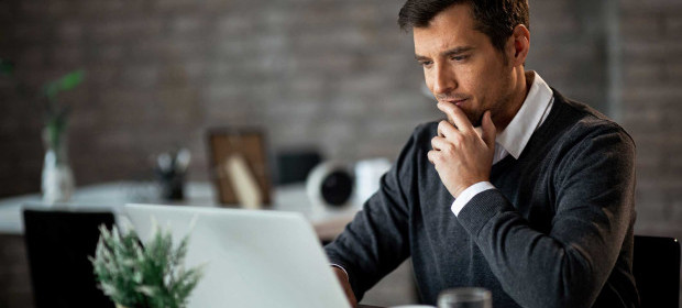 A man looking at a laptop screen concerned