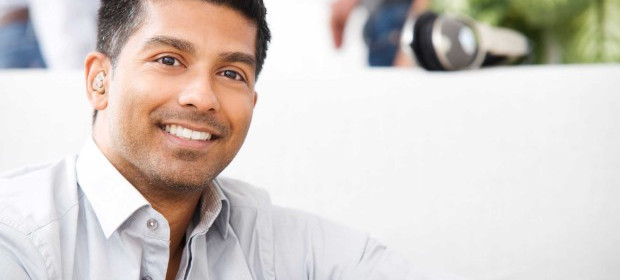 A man with a hearing aid smiling to the camera