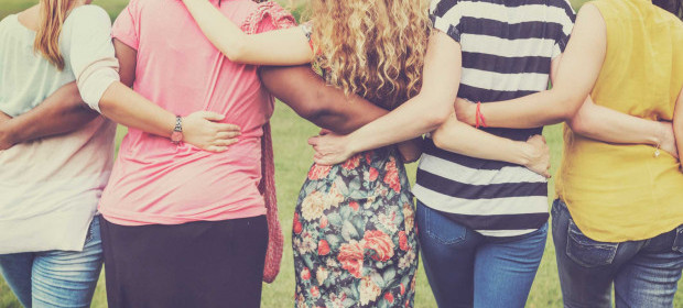 5 women standing with their backs to us linking arms