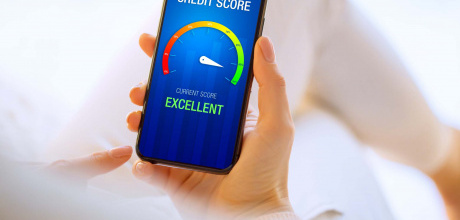 A person holding their phone showing an excellent credit score on the screen